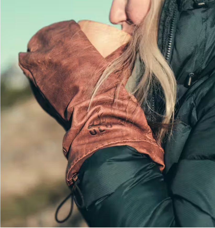 Skinnvotter fra ULU of Norway. Dame med lyst hår og boblejakke drikker varm drikke fra trekopp.